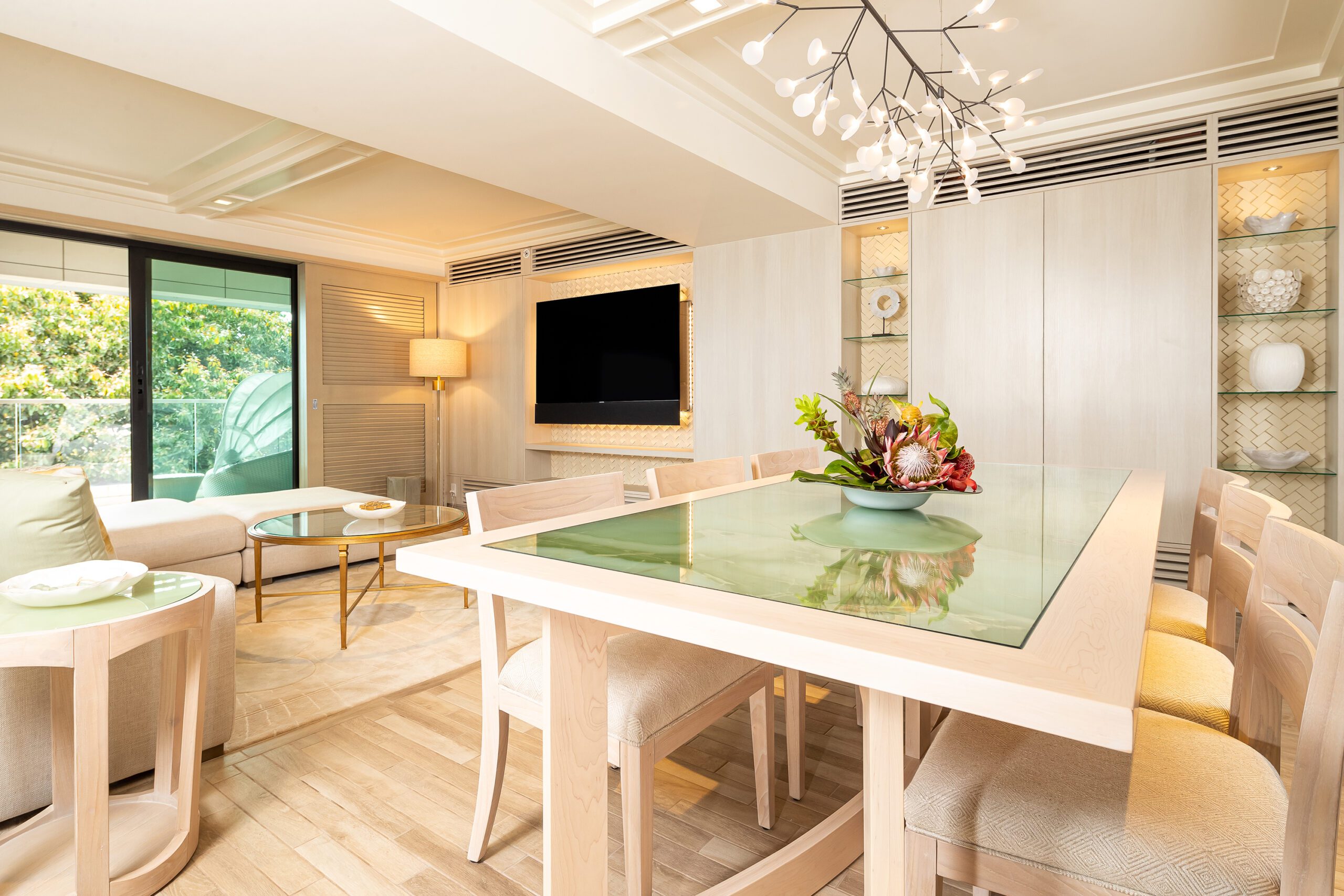 Dining area with table, chairs, decor, living area with couch, table, TV, and balcony.