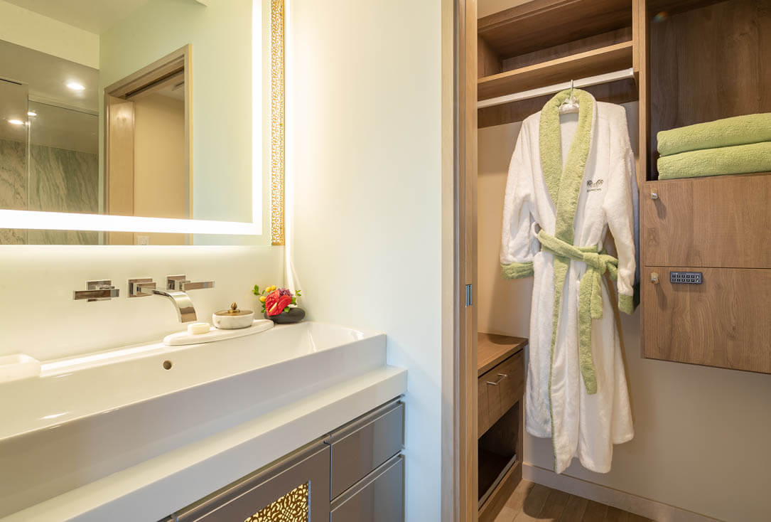 Bathroom sink, safe, and closet with a robe.