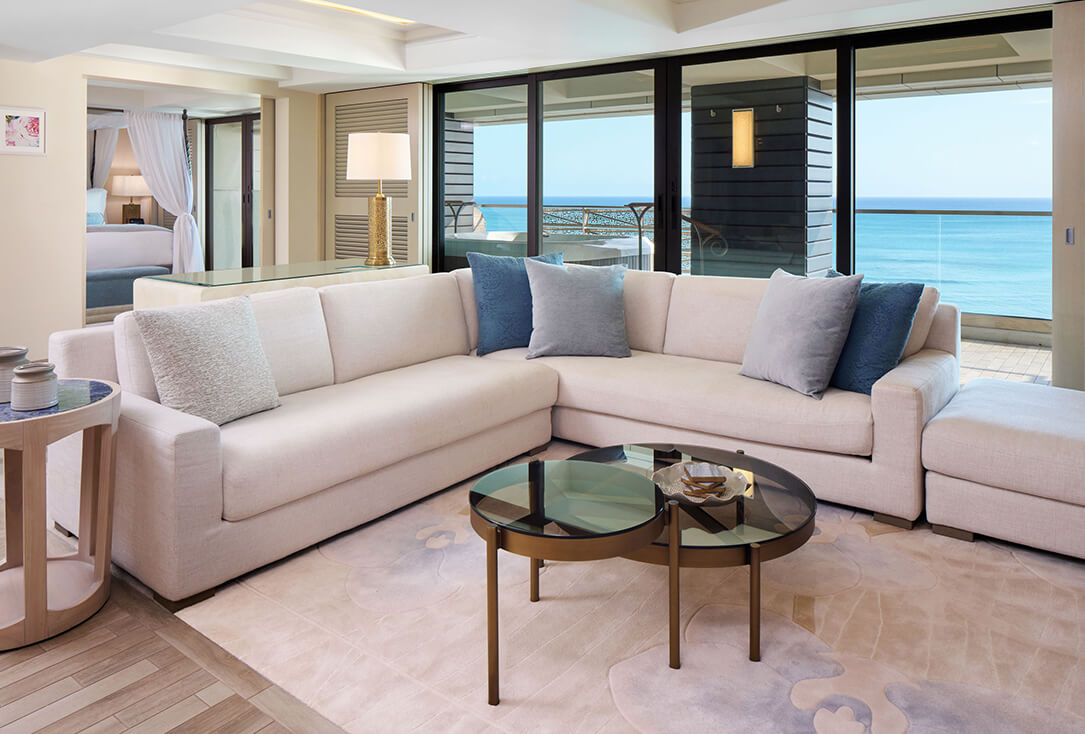 Living room with a sectional couch, coffee table, and balcony with ocean view.